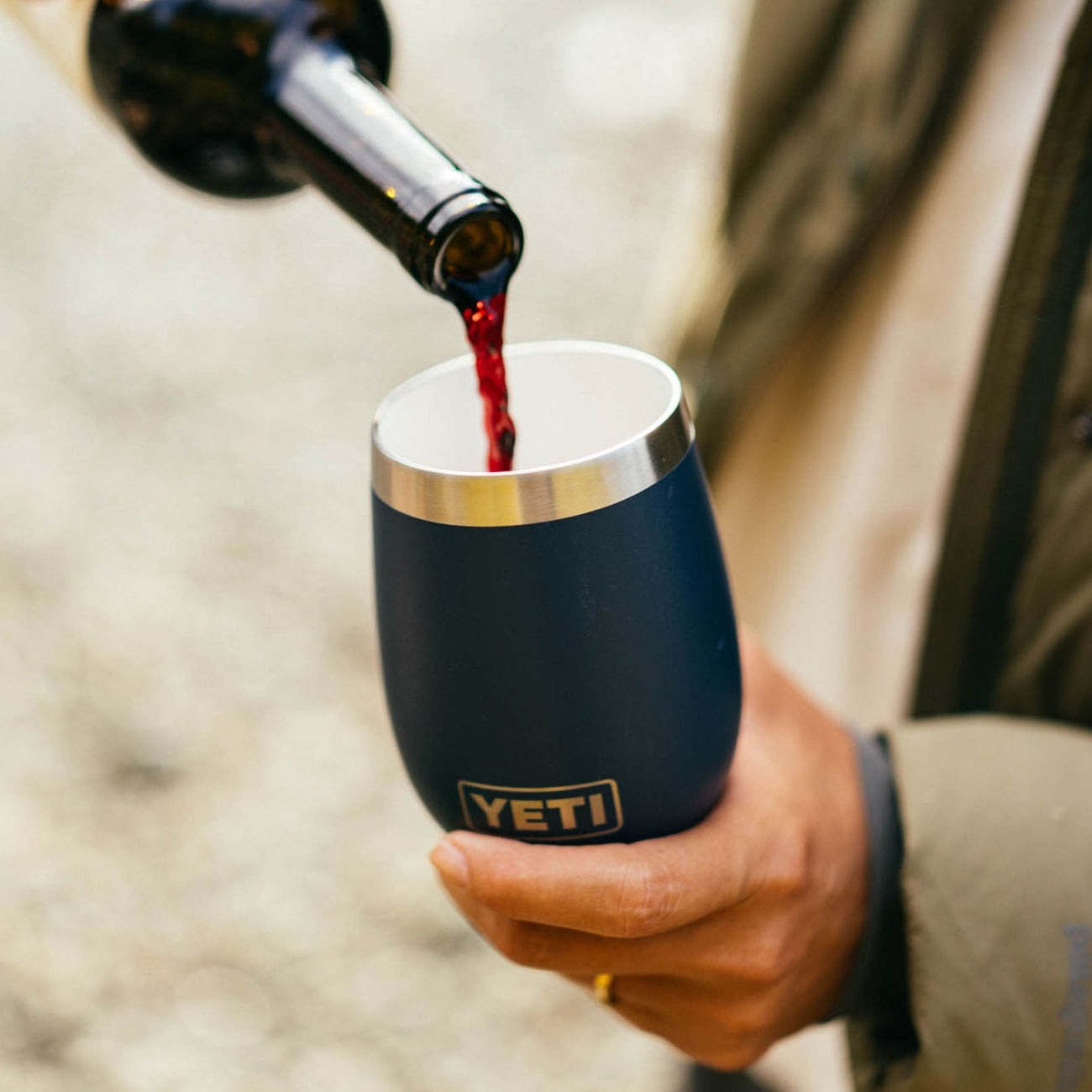 Person pouring red wine into a YETI-branded insulated wine tumbler.